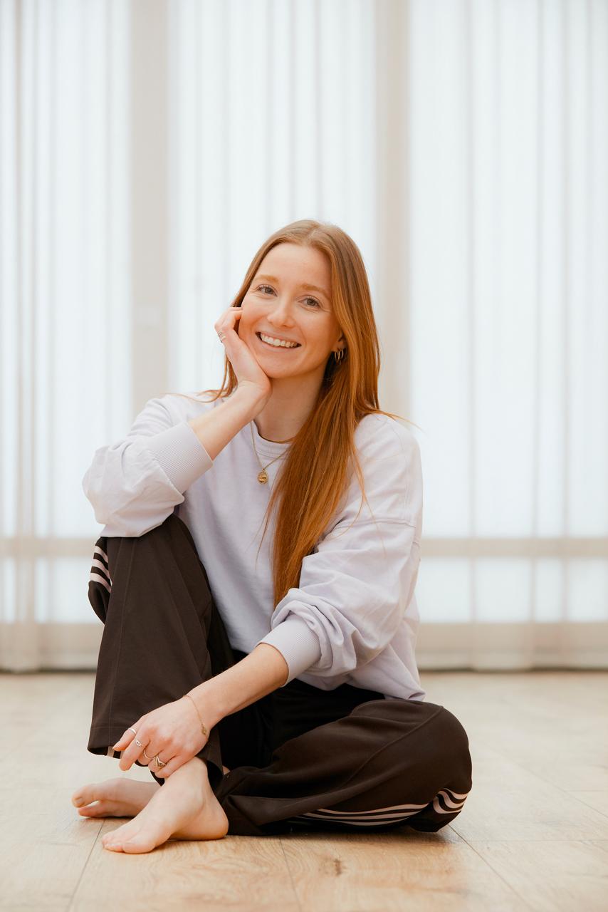 Founder of bees sitting on a studio floor, smiling